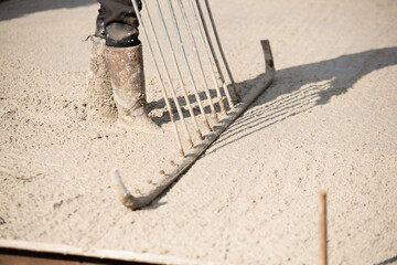 Close-up of Concreter leveling fresh concrete with screed dapple bar on building site