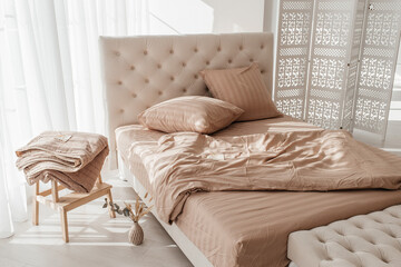 Cozy beige bedroom with tufted headboard and soft bedding in natural light.