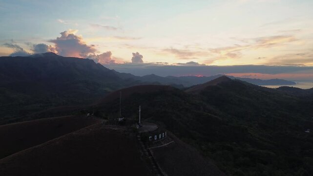 Wide aerial view of Mount Tapyas and surrounding Coron mountain ridges at sunrise with a glowing horizon over Palawan islands