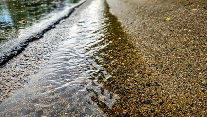 close-up of water flowing down a road curb after a rain. nature landscape or stormwater management design element.