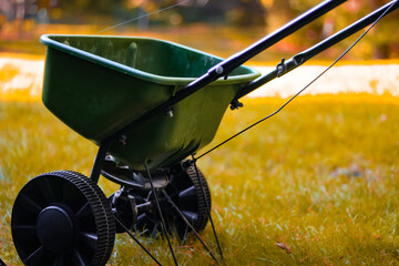Close-up of a broadcast seed or fertilizer spreader in a yard. beautiful bokeh light abstract...