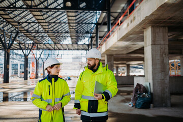Engineers discussing construction plans using a tablet on site.