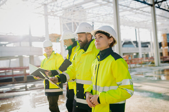 Team of engineers and construction workers inspecting building progress.