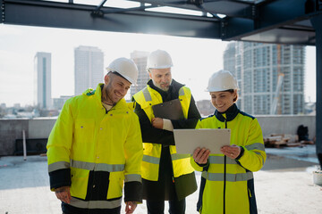 Team of engineers and construction workers inspecting building progress.