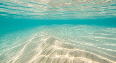 Underwater view of sandy seabed with clear turquoise water and surface reflections