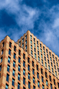 Angle view of orange-toned building facade with repetitive window pattern, bold geometry and vibrant sky contrast for business, construction or real estate imagery.