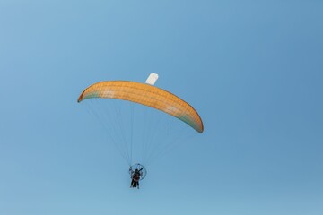 Paraglider soaring in clear blue sky