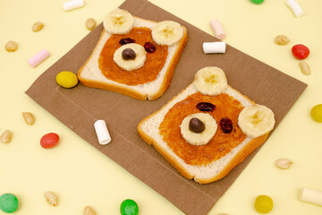 Funny cute bear faces sandwich toast bread with peanut butter, banana,nuts. Kids childrens sweet dessert healthy breakfast lunch food art on plate,top view