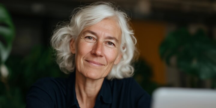 Mature woman with white hair engaged in a virtual meeting at home