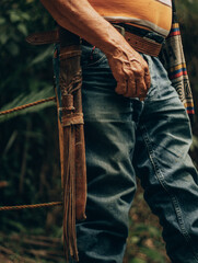 Worker’s hand with machete sheath hanging from belt on farm

