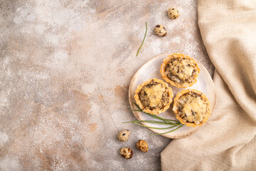 Tartlets with meat and cheese on brown concrete, linen textile. top view, flat lay, copy space