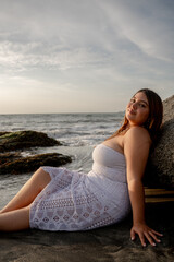 Plus-size woman rests on a rock on Santa Marta beach at sunset. High quality photo