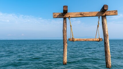 Wooden swing hanging from a rustic frame over calm blue ocean waters under a clear sky