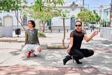 Two young LGBT dancers performing vogue choreography on city street
