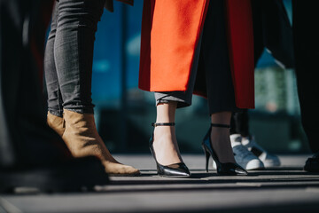 A group of people dressed stylishly outdoors, with focus on their elegant footwear, embodying modern fashion trends and individuality in a city environment.
