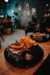 Ham sandwich with potato chips on a black plate at a cafe table overhead shot food photography culinary lunch delicious