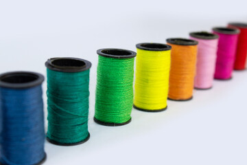 Bright colorful spools of thread on a white background. Ideal for sewing, tailoring, crafts, DIY projects, fashion design, and textile-related content.