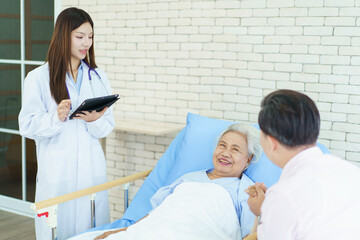 Fototapeta premium Asian man visiting his elderly mother in hospital and they have a conversation together.