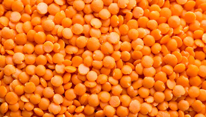 Close-up picture of lots of orange lentils, showing the small, flat, round shape, all together as a background.