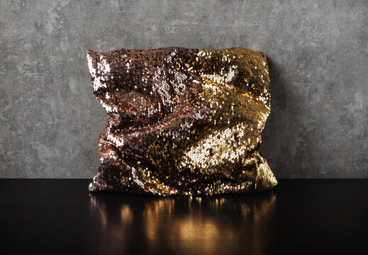 Glamorous golden sequin pillow glitter against a gray wall background.