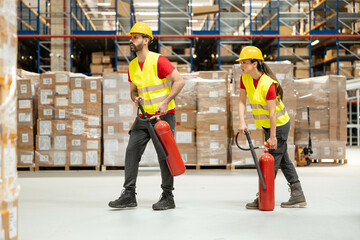Male and female employees walking with fire extinguishers during safety training or emergency preparedness drill.