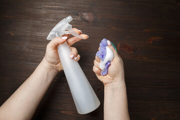 Kitchen cleaning concept. Cleansing kitchen sponge and detergent sprayer in woman hands.