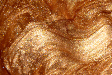 Texture background with golden shimmering cosmetic body spray or gel. Glowing backdrop.