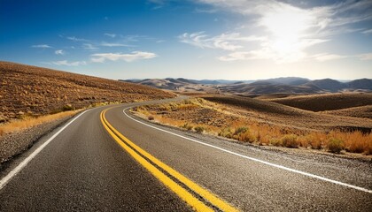 a wide angle perspective of a winding road with a yellow centerline cutting through dry barren hills representing an ongoing journey through a desolate yet picturesque landscape