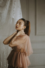 Beautiful woman in a pink dress with her eyes closed and hands on her neck