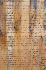 Fototapeta premium Close-up of a wooden panel featuring unrecognizable wood burn text in Russian language displaying texture and detail. Wood burning