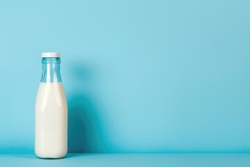 A bottle filled with fresh milk is sitting on a bright blue table