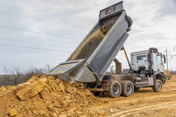 Dump truck unloads the waste onto the road. Road construction. dump truck with raised body