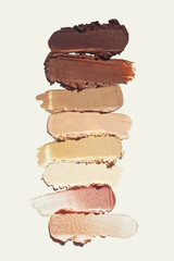 Cosmetic concealer or thick foundation smudge assortment set palette on beige background. Make up beauty product texture sample swatch from deep brown to highlighter