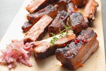 Delicious pork ribs, thyme and onion on grey table, closeup