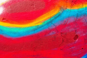 Vibrant rainbow graffiti texture with red, blue, yellow on rough surface. 90s style, trippy, fluorescent vibe. Street art, background, creative design, urban visuals, modern 90s, urban aesthetic.