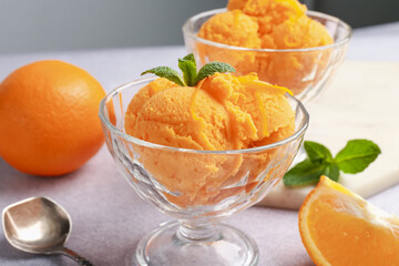 Tasty orange sorbet, fresh fruits and mint on light grey table, closeup