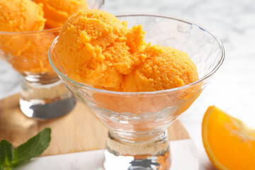 Balls of tasty orange sorbet in dessert bowls, fresh fruit and mint on table, closeup
