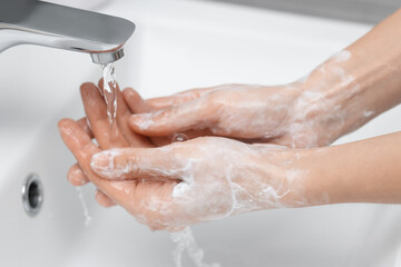 Fototapeta premium Woman washing hands at sink in bathroom, closeup
