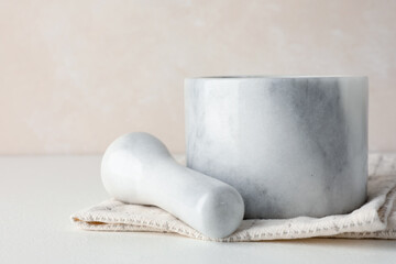 Marble mortar, pestle and cloth on white table, closeup