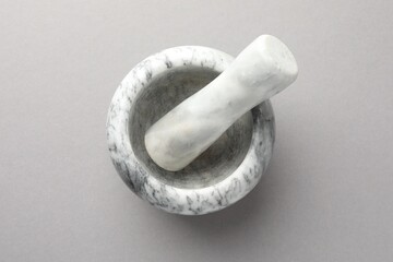 Marble mortar and pestle on light grey background, top view