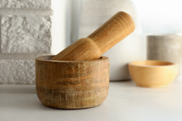 Wooden mortar and pestle on white table indoors, closeup