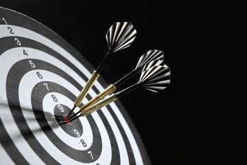 Targeting. Dart board with arrows on black background, closeup