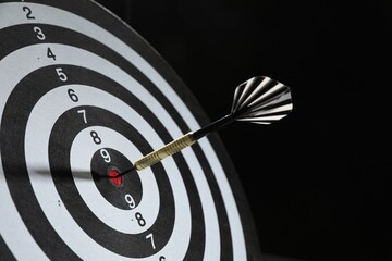 Targeting. Dart board with arrow on black background, closeup