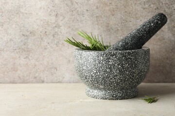 Stone mortar with rosemary and pestle on light table, closeup. Space for text