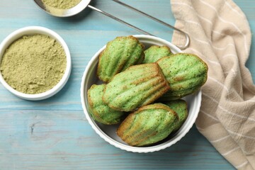 Tasty matcha madeleine cakes on light blue wooden table, flat lay