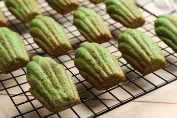 Tasty matcha madeleine cakes on light wooden table, closeup