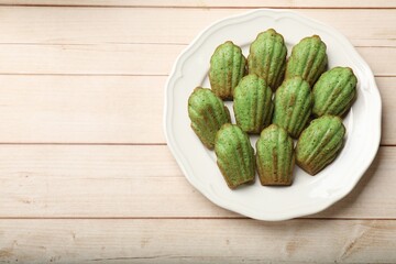 Tasty matcha madeleine cakes on light wooden table, top view. Space for text
