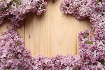 Frame of beautiful lilac flowers on wooden table, flat lay. Space for text