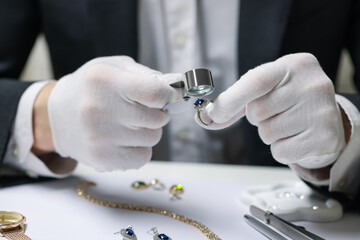 Appraiser with loupe evaluating luxury ring at white table, closeup