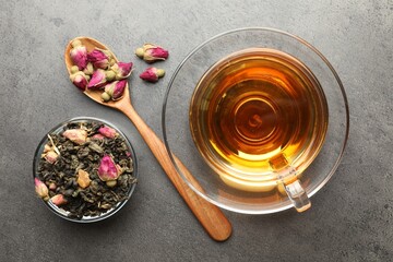 Aromatic herbal tea, dry leaves and flowers on grey table, flat lay